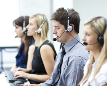 Attractive young man working in a call center with his colleagues